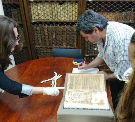 thumnail image of researchers examining an aintque book